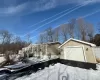 Snow covered property with an outbuilding, a garage, and a wooden deck