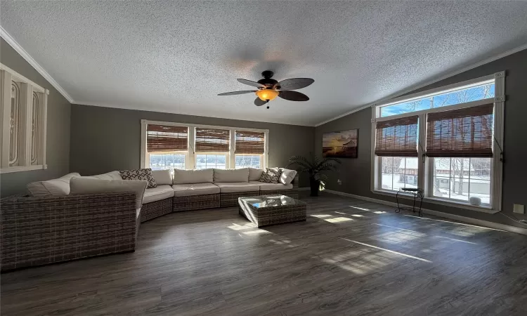 Living room with dark hardwood / wood-style floors, ceiling fan, a textured ceiling, and vaulted ceiling