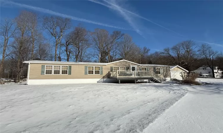 View of front facade with a garage, a deck, and an outbuilding