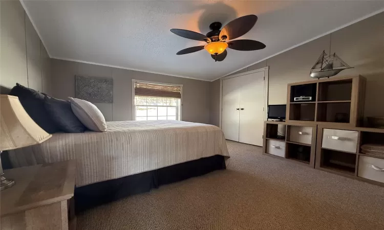 Bedroom featuring ceiling fan, crown molding, carpet floors, a textured ceiling, and vaulted ceiling