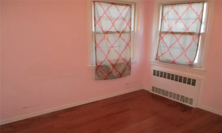 Empty room featuring radiator heating unit and wood-type flooring