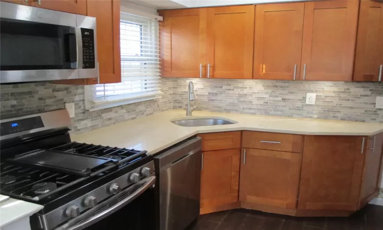 Kitchen with tasteful backsplash, sink, and appliances with stainless steel finishes