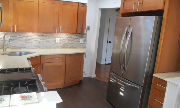 Kitchen featuring sink, stainless steel fridge, white gas range, tasteful backsplash, and dark hardwood / wood-style flooring