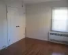 Empty room featuring dark hardwood / wood-style flooring, radiator, and ornamental molding