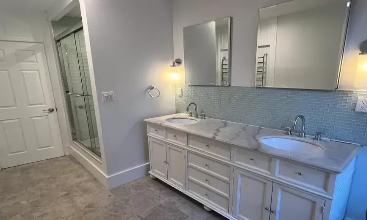 Bathroom featuring decorative backsplash, vanity, and walk in shower