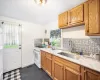 Kitchen featuring light stone countertops, white gas range oven, backsplash, dark tile patterned floors, and sink