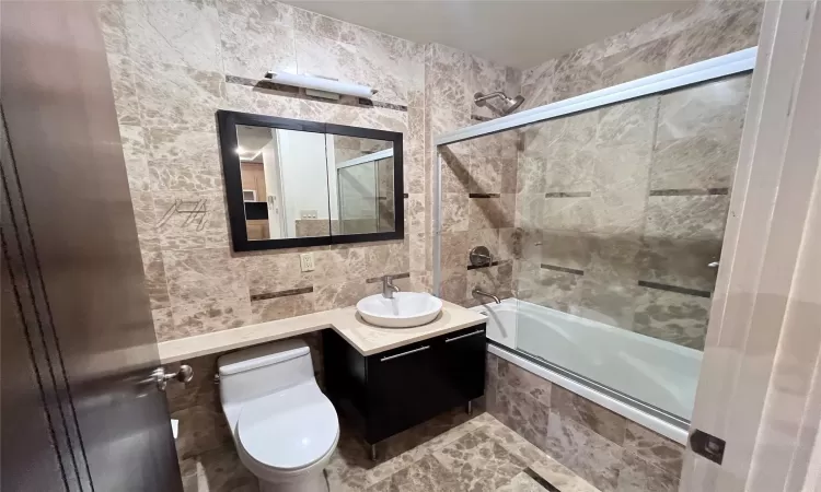 Full bathroom with vanity, toilet, and enclosed tub / shower combo