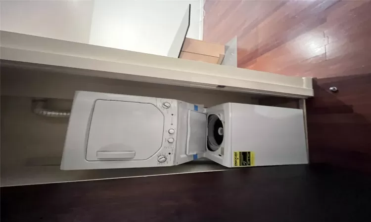 Laundry room with stacked washer and dryer and hardwood / wood-style flooring