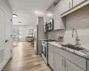 Kitchen featuring sink, decorative backsplash, appliances with stainless steel finishes, light hardwood / wood-style floors, and light stone counters