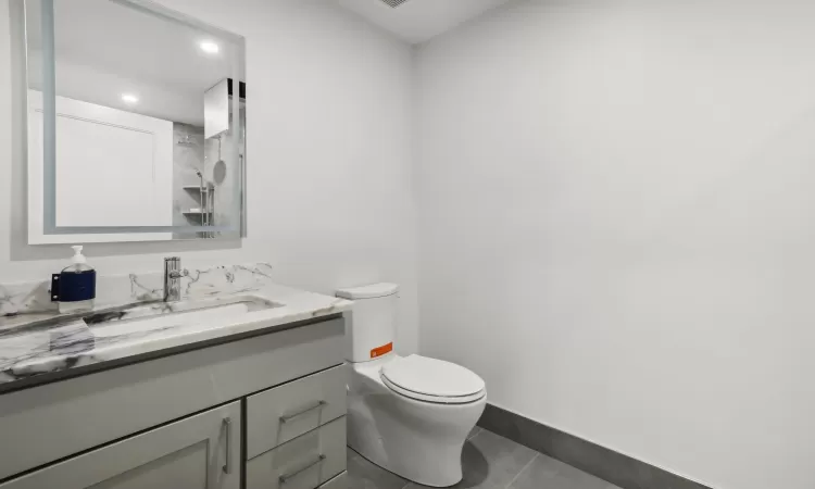 Bathroom featuring tile patterned floors, vanity, toilet, and a shower