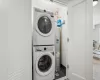 Laundry area with water heater and stacked washer and clothes dryer