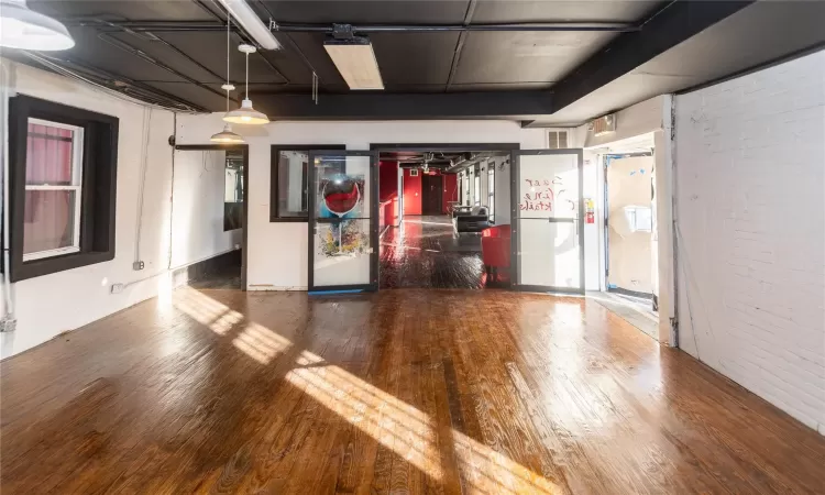 Empty room with hardwood / wood-style flooring and brick wall