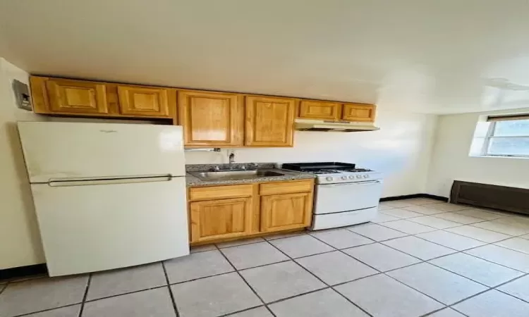 Kitchen with sink, light tile patterned flooring, and white appliances