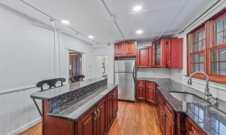 Kitchen with a kitchen breakfast bar, light wood-type flooring, sink, a center island, and stainless steel refrigerator