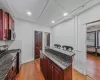 Kitchen featuring backsplash, dark stone countertops, stainless steel appliances, and hardwood / wood-style flooring