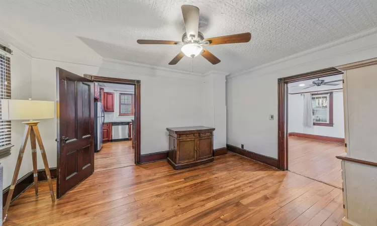 Empty room with hardwood / wood-style flooring, ceiling fan, and ornamental molding