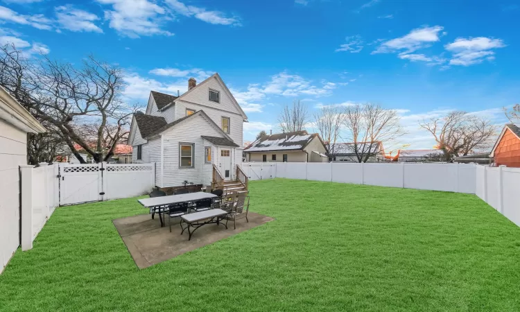 Back of house with a lawn and a patio