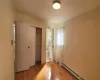 Unfurnished bedroom featuring a baseboard heating unit, light hardwood / wood-style flooring, a closet, and ensuite bath