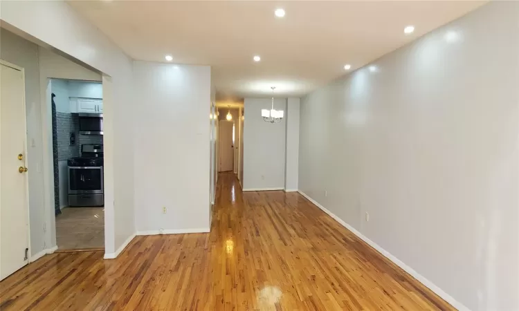 Hallway with light hardwood / wood-style flooring and an inviting chandelier