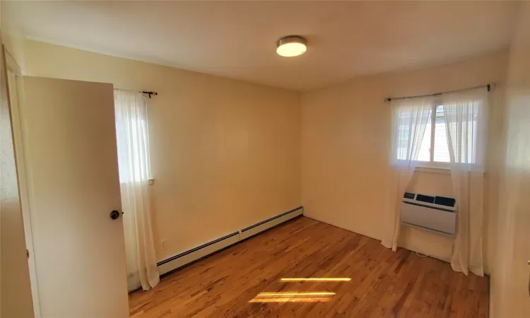 Spare room with baseboard heating, light hardwood / wood-style flooring, and a wall mounted air conditioner