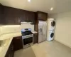 Kitchen with dark brown cabinetry, sink, stainless steel appliances, and stacked washer / drying machine