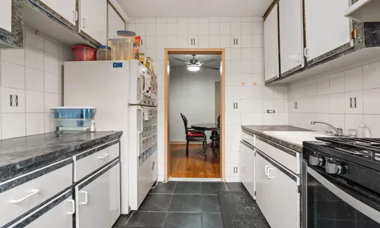 Kitchen featuring ceiling fan, sink, white cabinets, and white refrigerator