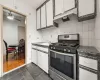 Kitchen featuring dark hardwood / wood-style flooring, ceiling fan, sink, stainless steel gas stove, and white cabinetry