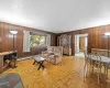 Living room featuring wooden walls, light parquet floors, and a baseboard radiator