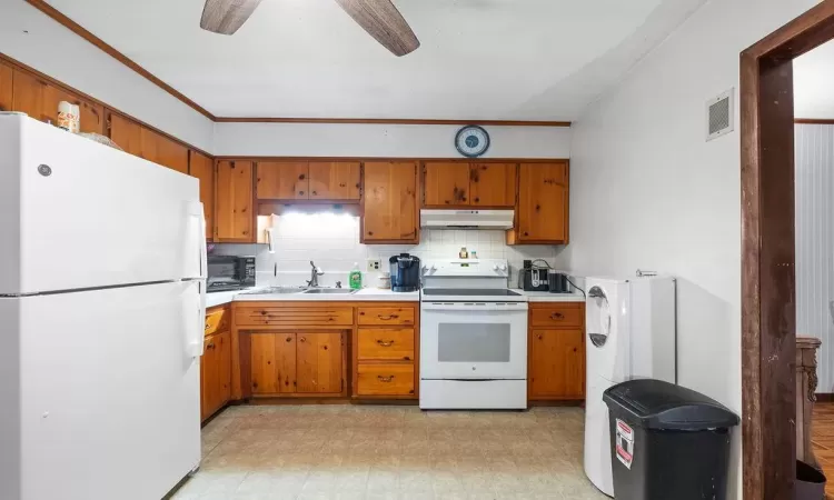 Kitchen featuring white appliances, backsplash, ceiling fan, and sink