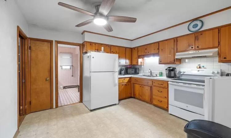 Kitchen featuring backsplash, ceiling fan, white appliances, and sink