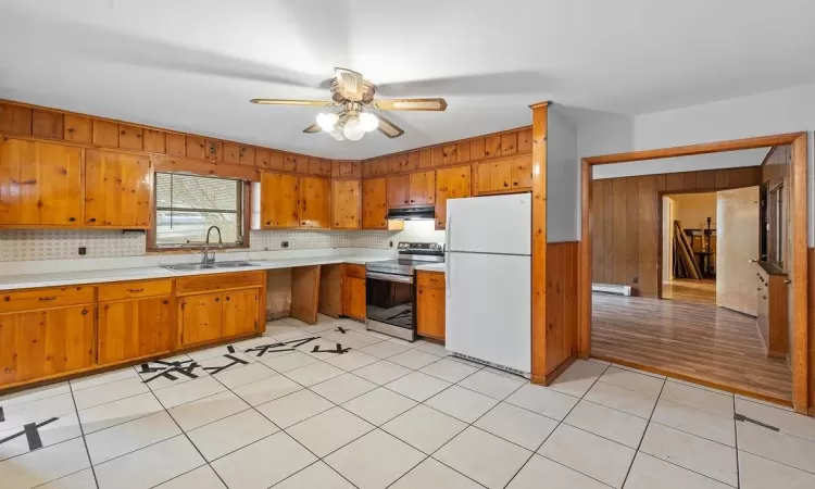 Kitchen featuring a baseboard heating unit, white refrigerator, electric stove, sink, and ceiling fan