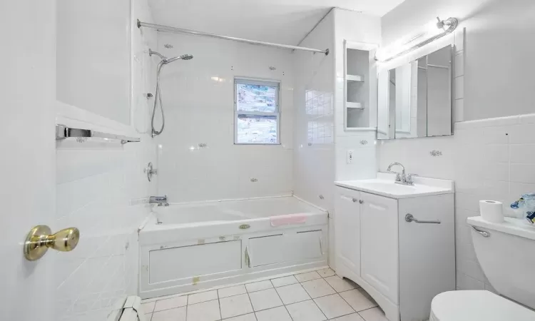 Full bathroom featuring vanity, tiled shower / bath, tile patterned flooring, toilet, and tile walls