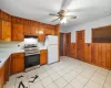 Kitchen with electric stove, wooden walls, ceiling fan, tasteful backsplash, and white fridge