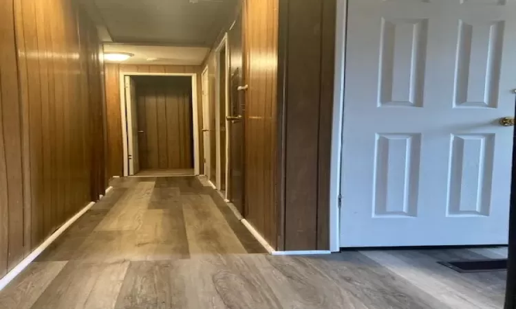 Corridor with dark hardwood / wood-style flooring and wood walls