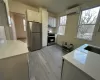 Kitchen with light stone countertops, white cabinetry, stainless steel appliances, an AC wall unit, and light hardwood / wood-style floors