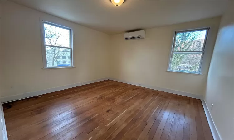 Empty room featuring a wall mounted air conditioner and hardwood / wood-style floors