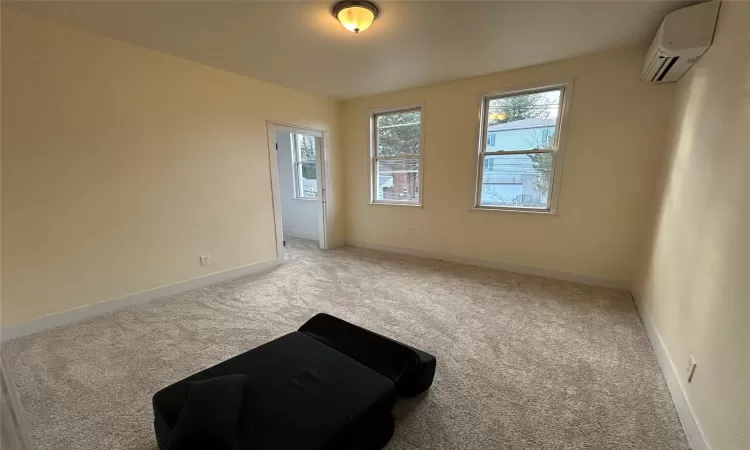 Carpeted empty room featuring a wall unit AC