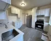 Kitchen featuring appliances with stainless steel finishes, light hardwood / wood-style flooring, white cabinetry, and sink