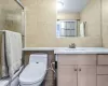 Bathroom featuring vanity, toilet, decorative backsplash, and tile walls