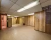 Basement with stainless steel fridge, a drop ceiling, and wooden walls