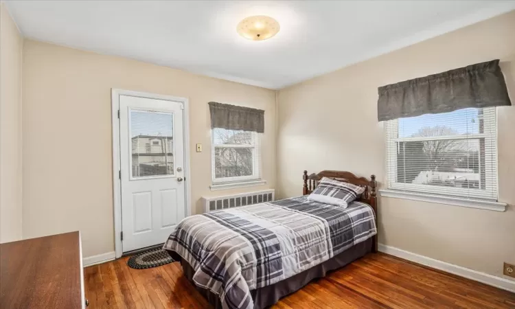 Bedroom with radiator and dark hardwood / wood-style flooring