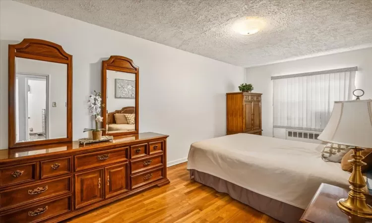 Bedroom with a textured ceiling and light wood-type flooring