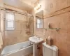 Bathroom featuring toilet, shower / bath combination with glass door, and tile walls