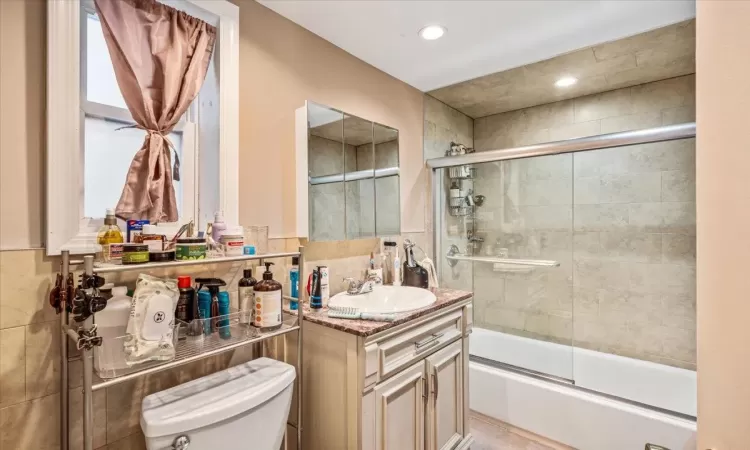 Full bathroom featuring vanity, toilet, and shower / bath combination with glass door