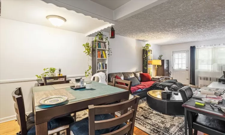 Dining room with a textured ceiling, hardwood / wood-style flooring, and radiator