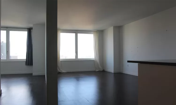 Unfurnished room featuring plenty of natural light and dark hardwood / wood-style flooring