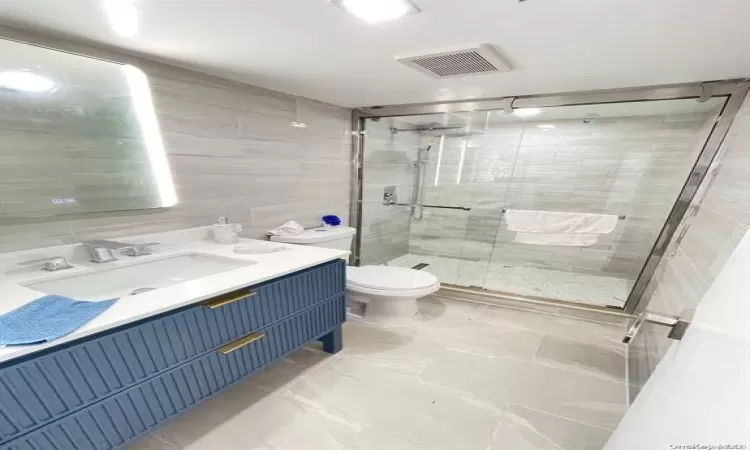 Bathroom with walk in shower, backsplash, toilet, vanity, and tile walls