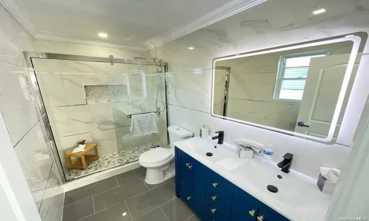 Bathroom featuring crown molding, a shower with shower door, and tile walls