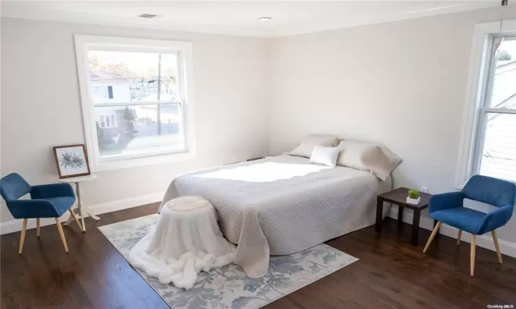 Bedroom with ornamental molding, dark wood-type flooring, and multiple windows