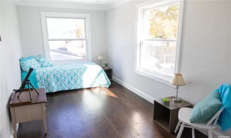 Bedroom with dark hardwood / wood-style flooring and ornamental molding